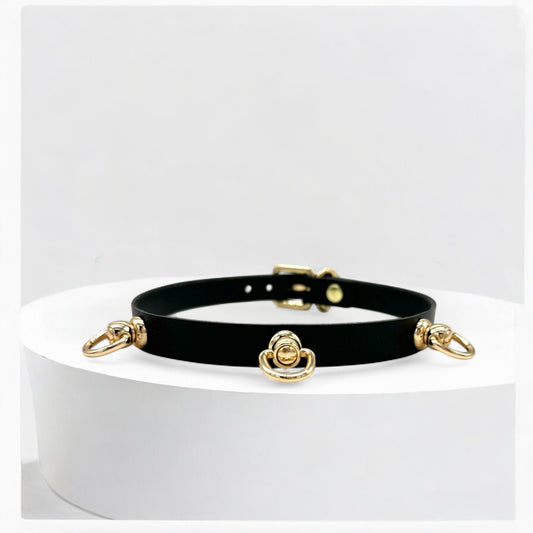 Black choker with gold accents on a white pedestal